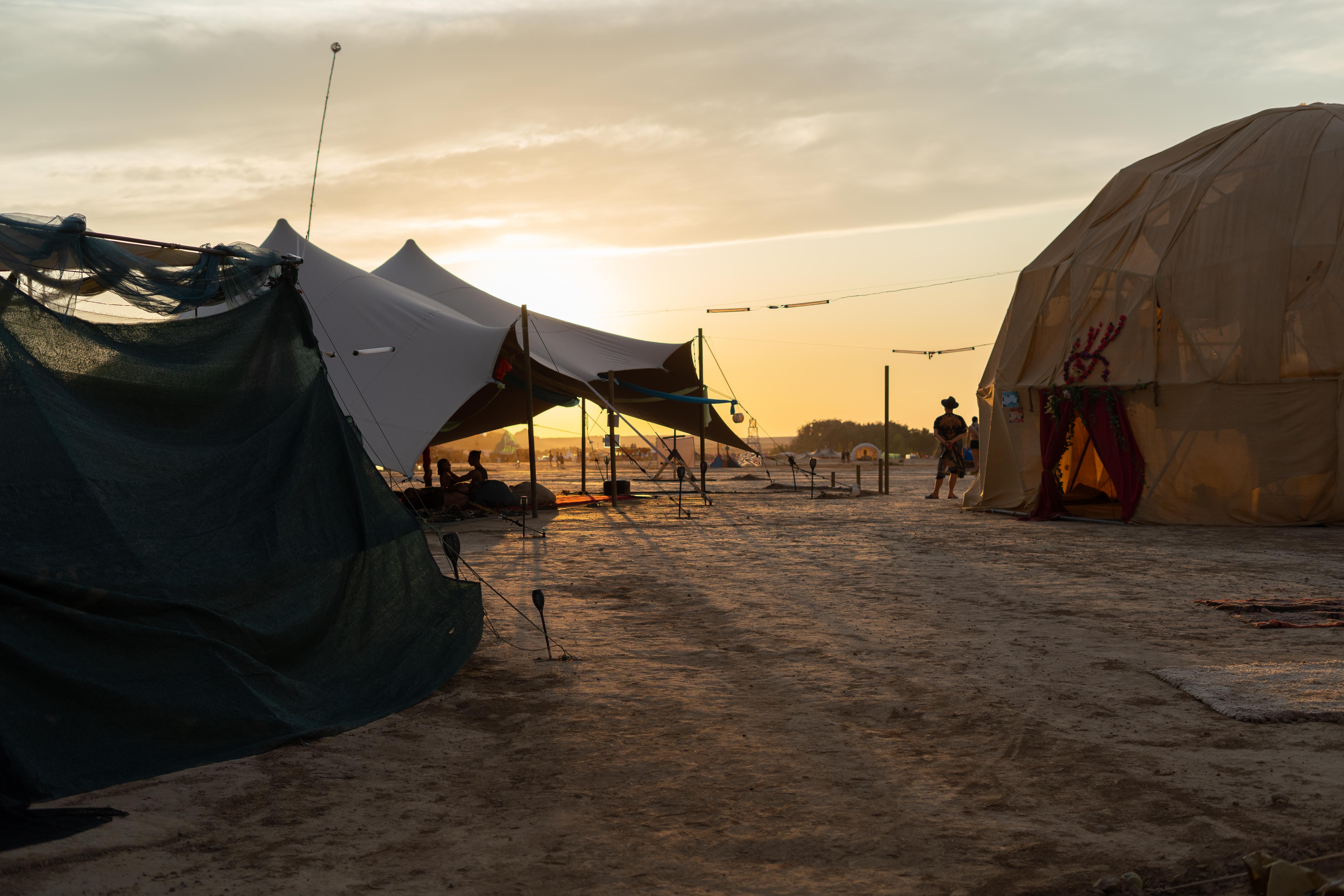 Barrio tents and structures silhouetted against sunset in Spain